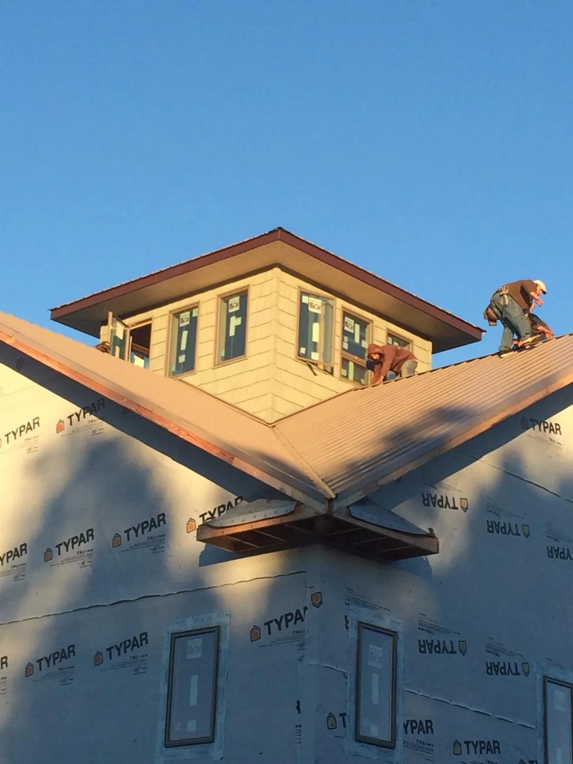 Roofers working around a rooftop cupola on a new metal roof at sunset — Roof Waterproofing in Johnstown by Roofing Brothers